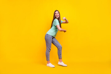 Full body profile photo of funny brunette hairdo young lady dance wear t-shirt jeans sneakers isolated on yellow background