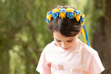 Little embarrassed girl in Ukrainian national wreath decoration