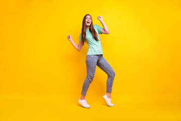 Full length photo of cool brunette hairdo young lady dance wear t-shirt jeans sneakers isolated on yellow background