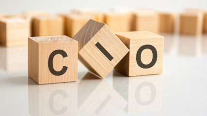 three wooden blocks with the letters CIO on the bright surface of a gray table, business concept