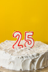 Closeup of a white meringue cake decorated with number 25 candles