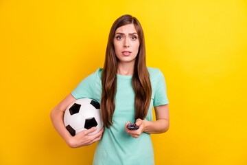 Photo of sad brunette hairdo young lady hold ball switch tv wear teal t-shirt isolated on yellow color background