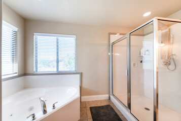 Fototapeta na wymiar Bathroom interior with corner bathtub and shower stall with glass and aluminum frame