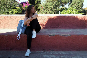 Woman with gym bag resting in the park after workout