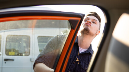 Naklejka premium man looking into orange car