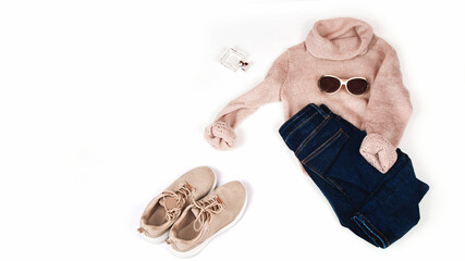 Pastel knitted sweater with denim pants, sneakers and accessories on a white background. Autumn and winter clothing. Shop, sale, fashion concept.