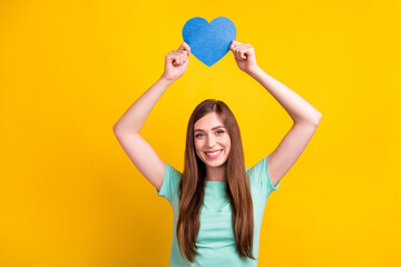 Fototapeta na wymiar Photo of lovely brunette hairdo young lady hold heart wear teal t-shirt isolated on yellow color background