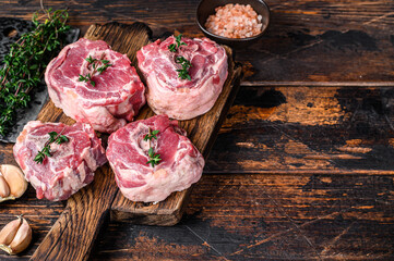 Raw mutton lamb neck meat on a butcher board with cleaver. Dark wooden background. Top view. Copy...