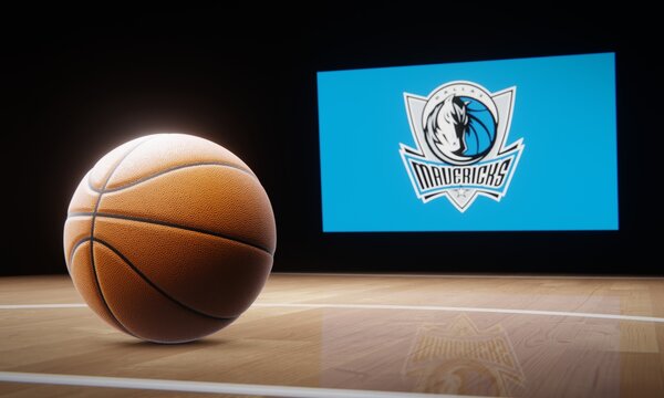 Basketball in foreground with logo of NBA team Dallas Mavericks projected on screen in background. Editorial 3D illustration