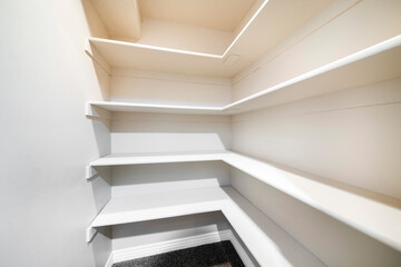 White linen closet with wall mounted shelves and carpeted floor