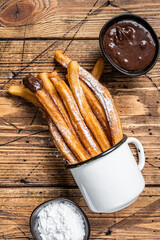Churros with sugar and chocolate sauce. wooden background. Top view