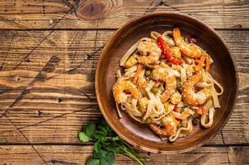 Udon stir-fry noodles with shrimp prawns in a wooden bowl. wooden background. Top view. Copy space