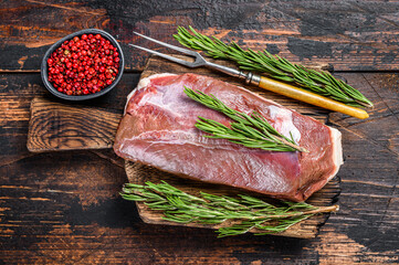 Raw fresh duck meat breast fillet steak with herbs and rosemary. Dark wooden background. Top view