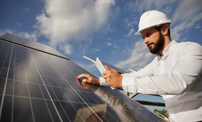 Concentrated male inspector checking solar panels at construction site