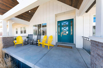 Porch of a house with blue green door and lounge chairs