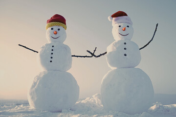 Couple Snowman in winter outdoor. New year snowmen from snow in santa hat