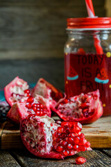 Pomegranate juice, home cooking, folk recipes, traditional medicine, pomegranate cutting. Pomegranate fruit and pomegranate juice in a glass on a wooden table.