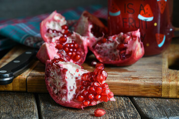 Pomegranate juice, home cooking, folk recipes, traditional medicine, pomegranate cutting. Pomegranate fruit and pomegranate juice in a glass on a wooden table.