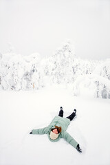 Naklejka na ściany i meble Happy girl lying down on snow