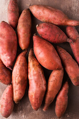Sweet potato on a brown background. Exotic food. A fresh crop of vegetables. Raw sweet potato. Organic food