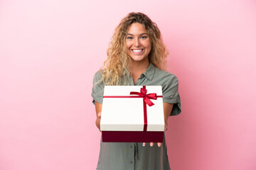 Girl with curly hair isolated on pink background pregnant and holding a gift