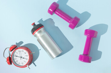 Alarm clock, weights and water bottle. Early rise idea. Good habits concept.