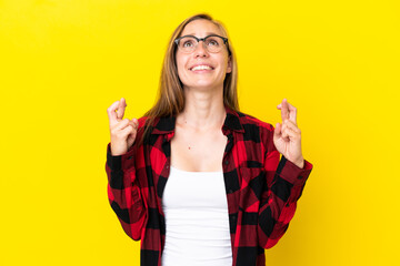 Young English woman isolated on yellow background with fingers crossing and wishing the best
