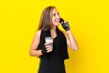 Young sport English woman isolated on white background holding coffee to take away and a mobile