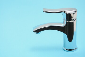 Single handle water tap on light blue background, closeup