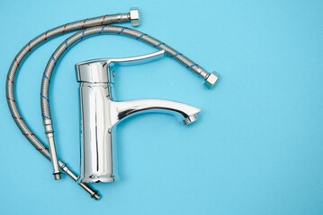 Single handle water tap on light blue background. New chrome or steel mixer tap .