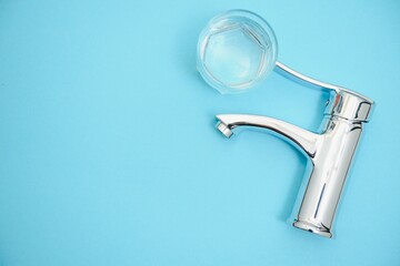 Single handle water tap on light blue background. New chrome or steel mixer tap .