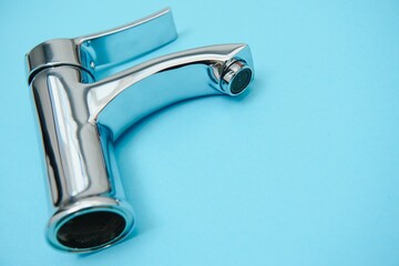 Single handle water tap on light blue background, closeup