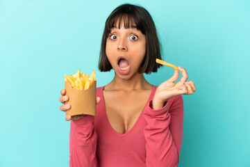 Young brunette woman holding fried chips over isolated blue background