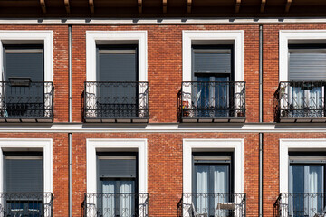 Naklejka premium Orange brick facade with wrought iron balconies