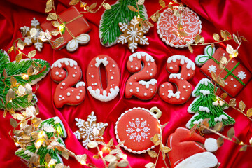 Obraz premium Banner for Christmas and New Year gingerbread cookies numbers 2023, snowflakes, Santa hat, Christmas trees, garlands on red silk fabric background