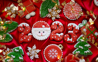 Banner for Christmas and New Year gingerbread cookies numbers 2023, snowflakes, Santa hat, Christmas trees, garlands on red silk fabric background