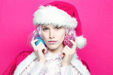 Young woman or cute girl in christmas santa hat holds Christmas balls on pink background. Closeup face portrait
