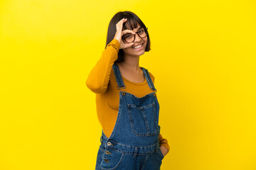 Young pregnant woman over isolated yellow background showing ok sign with fingers