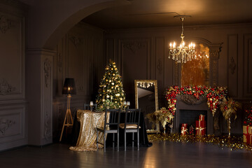 Interior of luxury dark living room with fireplace, comfortable sofa and chandelier decorated with Christmas tree and gifts
