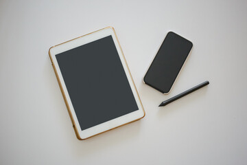 Tablet, phone and pen lie in the office on a white table