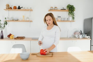 pregnant woman slicing vegetables at home in the kitchen