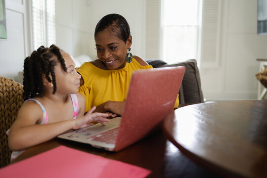 Mother and daughter using laptop at home