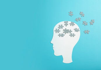 Dementia, alzheimer, memory and mental brain health concept background. Paper head with puzzle pieces on a blue background