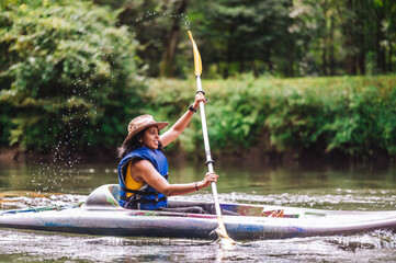 Woman in hat kayaking on river 