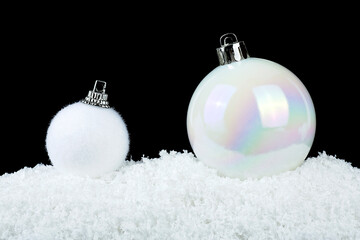 Two white christmas balls in snow on a black background