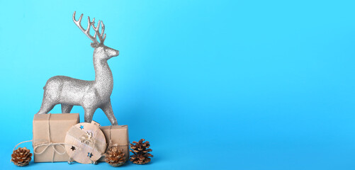 Reindeer with Christmas decor and gifts on blue background with space for text