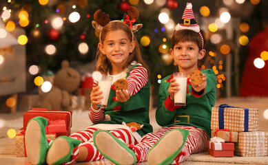 Cute little elves drinking milk with cookies at home on Christmas eve