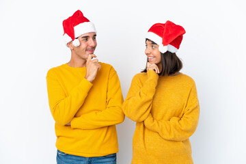 Young mixed race couple celebrating Christmas isolated on white background looking looking at each other