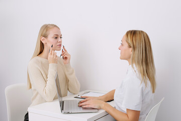 Consultation in cosmetology clinic. Female professional beauty doctor talking with pretty young...