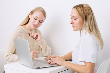 Consultation in cosmetology clinic. Female professional beauty doctor talking with pretty young female.